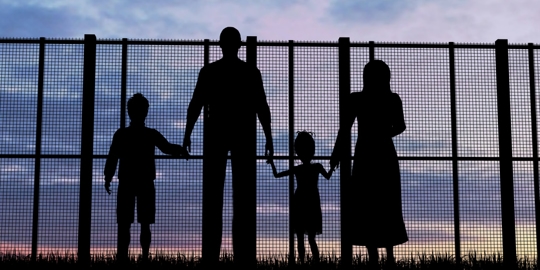 silhouette of family in front of fence