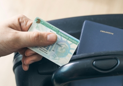 Man holding permanent resident (green) card. United States passport   on suitcase. Application to register permanent residence.