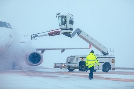 Deicing of airplane before flight. Winter frosty night and ground service at airport during snowfall.
