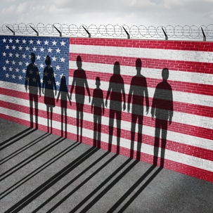 American immigration and United States refugee crisis concept as people on a border wall with a US flag as a social issue on refugees or illegal immigrants with the shadow of a group of migrants.